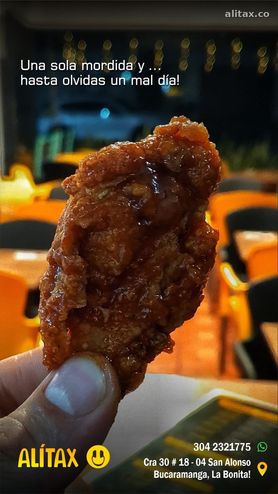 Una alita con salsa en la mano